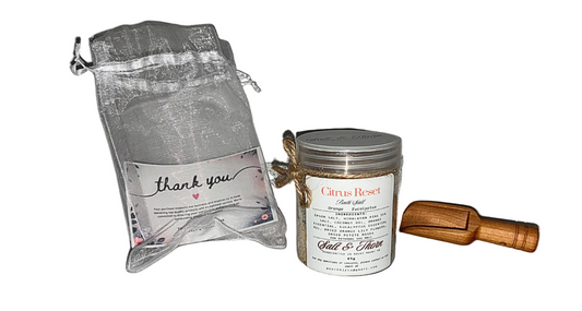 Bath and body product set with a candle, bag, and wooden scoop on a white background