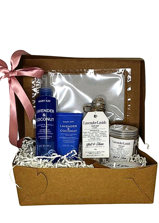 Gift basket with lavender and coconut products including a bottle, jar, and other items in a brown box with a pink ribbon.